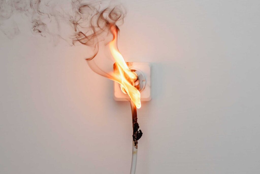 Electrical outlet with a burning and smoking power cord.