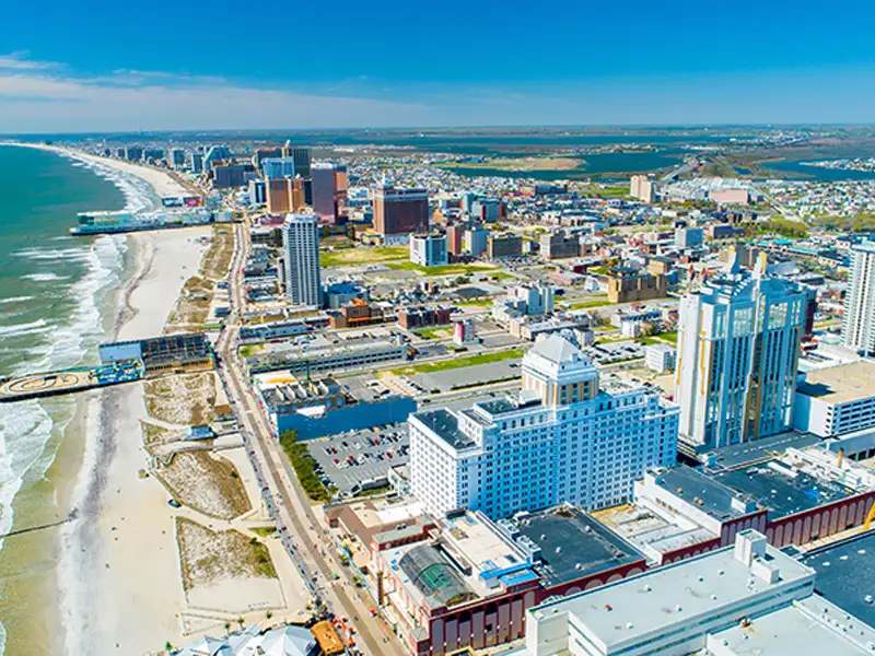 Aerial view of a coastal city with high-rise buildings along a sandy beach and ocean waves.