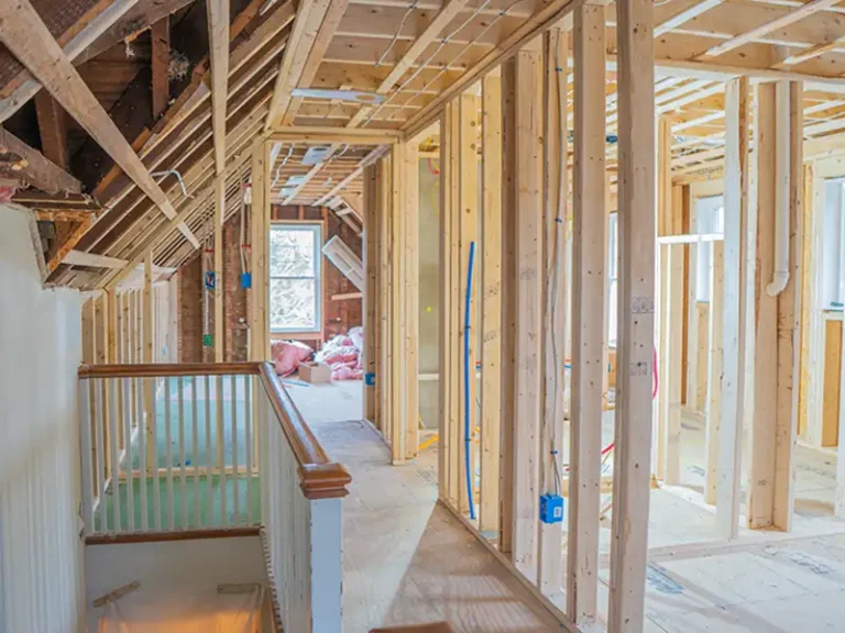 Interior of a house under construction with exposed wooden framing and electrical wiring.