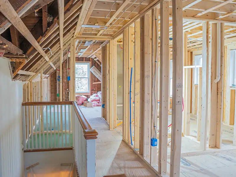 Interior of a house under construction with exposed wooden framing and electrical wiring.