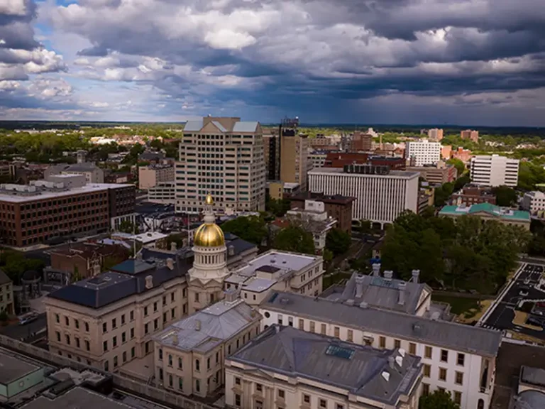 Cityscape with a prominent building featuring a gold dome under a cloudy sky.
