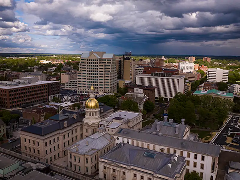 Cityscape with a prominent building featuring a gold dome under a cloudy sky.